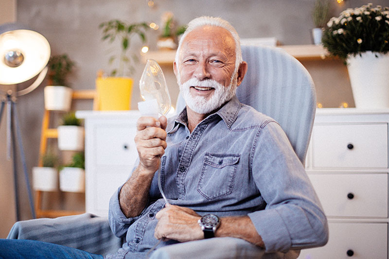 Senior man with COPD holding his oxygen face mask